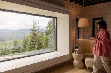 Kadınlar doğadaki ahşap evde dinlenirken dağlarda manzaranın tadını çıkarırlar. Eğlence ve ev konforu