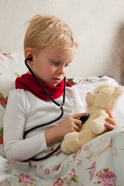 Sick boy is playing with a stethoscope — Stock Photo, Image
