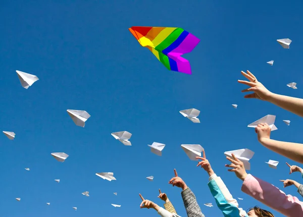 Mensen handen lanceren papieren vliegtuigen in de blauwe lucht Stockafbeelding