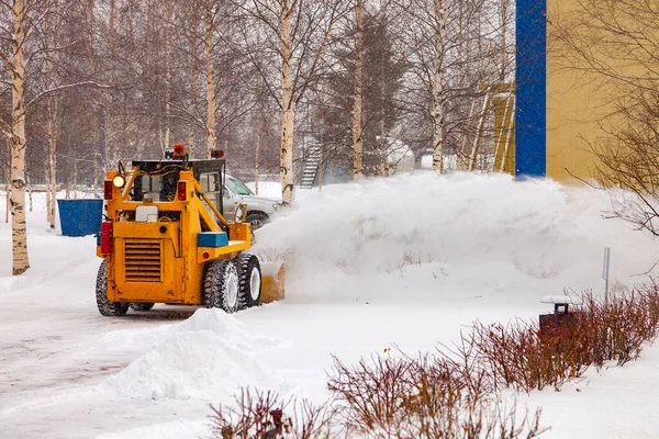 Tractor with snow plow blade clears road in city from fresh fallen snow — Stock Photo, Image