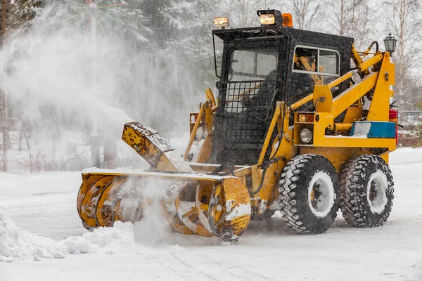 Tractor con hoja de arado de nieve despeja el camino en la ciudad de la nieve fresca caída Imagen de archivo