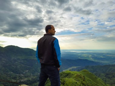 Kurseong Darjeeling Batı Bengal Hindistan 'da sabah dramatik bir gökyüzü ile dağın tepesinde duran bir adam görüntülendi..