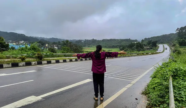 雨の日にターマック道路の勝利位置に立つ少女を孤立させ — ストック写真