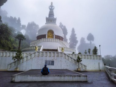 Budist shanti stupa 'da meditasyon yapan bir adam sabah bulanık sis ile kaplanmış olarak Japon tapınağı shanti stupa darjeeling Batı Bengal Hindistan' da çekilmiştir..