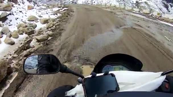 バックグランドに雪の帽子の山がある人里離れたヒマラヤの孤立した道路で自転車に乗る — ストック動画