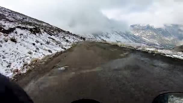 バックグランドに雪の帽子の山がある人里離れたヒマラヤの孤立した道路で自転車に乗る — ストック動画