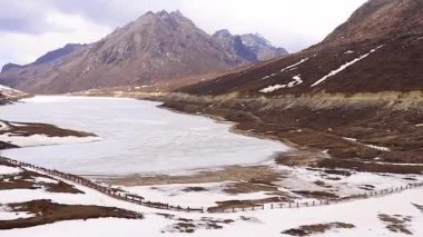 Donmuş sela gölü, kar örtüsü dağları ve parlak mavi gökyüzü sabah düz açıyla.