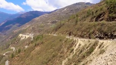 Kavisli yolu olan dağ vadisi ve tepeden güneşli bir günde parlak mavi gökyüzü.