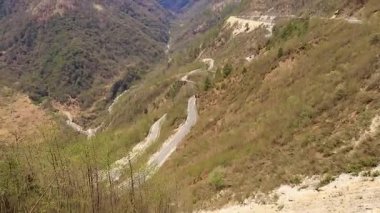 Kavisli yolu olan dağ vadisi ve tepeden güneşli bir günde parlak mavi gökyüzü.