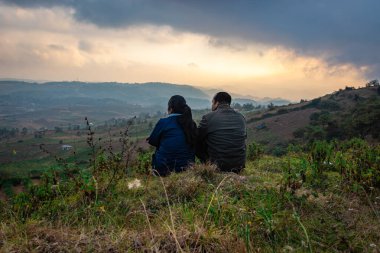Genç çift dağın tepesinde oturuyor sisli tepe arkaplanı ve dramatik gökyüzü ile sabah görüntüsü Badda Peak Shillong Meghalaya Hindistan 'da çekiliyor..