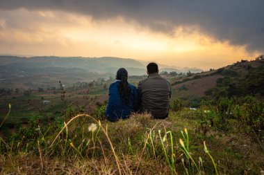 Genç çift dağın tepesinde oturuyor sisli tepe arkaplanı ve dramatik gökyüzü ile sabah görüntüsü Badda Peak Shillong Meghalaya Hindistan 'da çekiliyor..