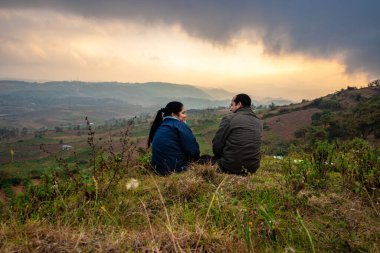 Genç çift dağın tepesinde oturuyor sisli tepe arkaplanı ve dramatik gökyüzü ile sabah görüntüsü Badda Peak Shillong Meghalaya Hindistan 'da çekiliyor..