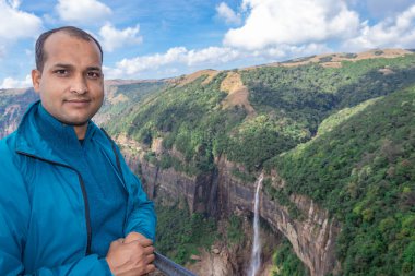 Nohkalikai Şelalesi Cherrapunji Meghalaya Hindistan 'da gündüz vakti yeşil ormanlarla kaplı dağların tepesinden akan şelaleli genç adam görülüyor..