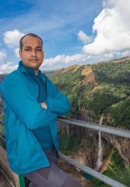 Nohkalikai Şelalesi Cherrapunji Meghalaya Hindistan 'da gündüz vakti yeşil ormanlarla kaplı dağların tepesinden akan şelaleli genç adam görülüyor..