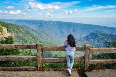 Genç kız, öğleden sonra açık mavi gökyüzü ile dağ sırasını seyrediyor. Düz açı görüntüsü, yedi kardeş şelale Cherrapunji meghalaya Hindistan 'da çekildi..