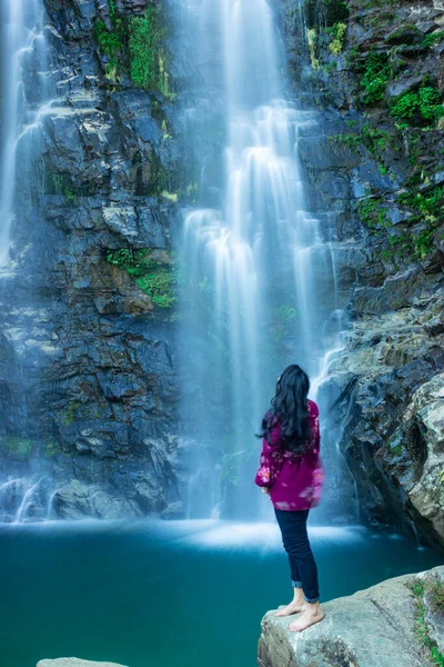 Şelalenin dağdan düşüşünü seyreden genç kız sabah bulanık su yüzeyiyle Şükran Günü 'nde Shillong Meghalaya Hindistan' da görüntülenir..