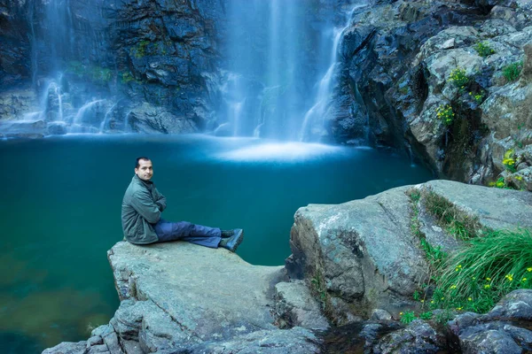 Şelaledeki genç adam, sakin ve bulanık su yüzeyiyle dağdan düşerken Şükran Günü 'nde Shillong Meghalaya Hindistan' da görüntülenir..