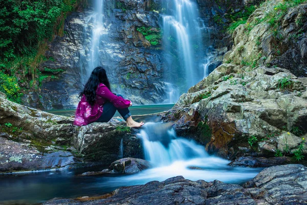 在桑宁市西隆美高拉雅地区拍摄了一个女孩坐在岩石上 瀑布从山上滑落 水面模糊的画面 — 图库照片