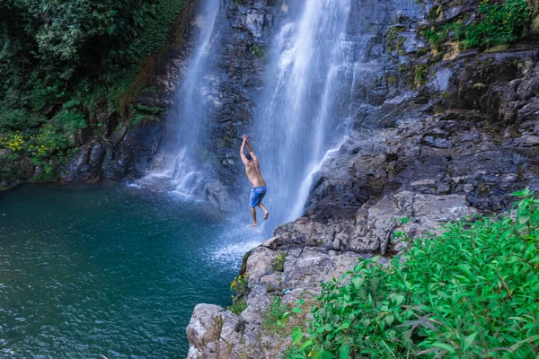 Ung Man Hoppar Från Klippan Vid Naturliga Vattenfall Blått Vatten — Stockfoto