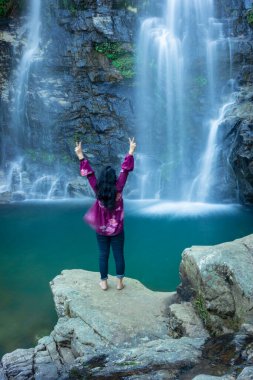 Şelalenin dağdan düşüşünü seyreden genç kız sabah bulanık su yüzeyiyle Şükran Günü 'nde Shillong Meghalaya Hindistan' da görüntülenir..