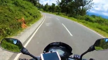 Yeşil ormandaki asfalt yolda motosiklet sürücüsü açısından...