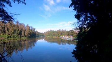 Saf durgun su gölü, huzur veren mavi gökyüzünün yansıması ve Ooty Lake Tamilnadu Hindistan 'da çekilmiş yeşil ormanlarla çevrili..