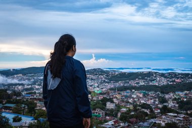 Şehir merkezindeki şehir manzarasını seyreden genç bir kız, akşam üzeri dağdan dramatik bulutlu bir gökyüzü ile Hindistan 'ın Shillong meghalaya bölgesinde çekiliyor..