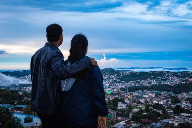Şehir merkezindeki şehir manzarasını seyreden genç bir çift, akşam üzeri dağların tepesinden dramatik bulutlu gökyüzü görüntüsüyle, Şillong meghalaya Hindistan 'da çekiliyor..
