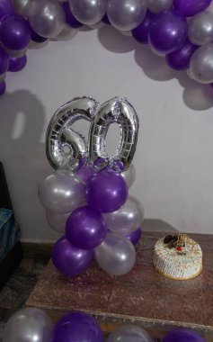 Farklı açılardan gelen renkli balonlar ve beyaz pastalarla 60. yaş günü süslemeleri.