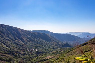 Dağlar, yoğun yeşil ormanlarla ve parlak mavi gökyüzüyle kaplı. Sabah görüntüsü Hindistan 'da çekiliyor..