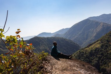 Yeşil ormanları ve sisli mavi gökyüzü ile dağların tepesindeki izole genç adam düz açıdan Mawryngkhang trek meghalaya Hindistan 'da çekilmiştir..