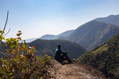 Yeşil ormanları ve sisli mavi gökyüzü ile dağların tepesindeki izole genç adam düz açıdan Mawryngkhang trek meghalaya Hindistan 'da çekilmiştir..