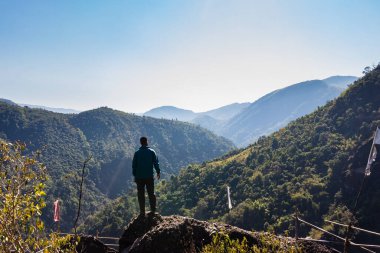 Yeşil ormanları ve sisli mavi gökyüzü ile dağların tepesindeki izole genç adam düz açıdan Mawryngkhang trek meghalaya Hindistan 'da çekilmiştir..