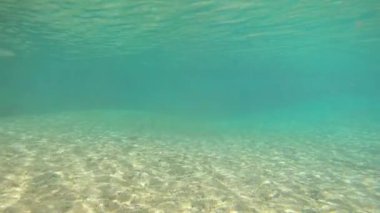 Genç adam doğal şelalede yürüyor mavi berrak su altında çekim