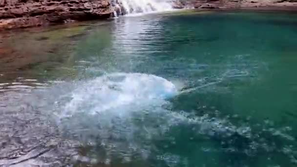 Junger Mann Springt Und Schwimmt Blauen Klaren Wasser Des Wasserfalls — Stockvideo