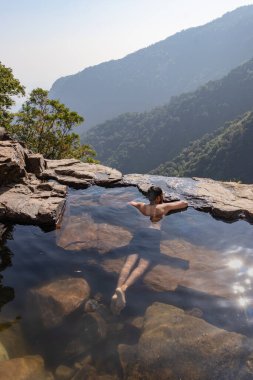Dağ yamacındaki doğal yüzme havuzunun tadını çıkaran bir adam. Nognah meghalaya Hindistan 'da çekilmiş bir görüntü..