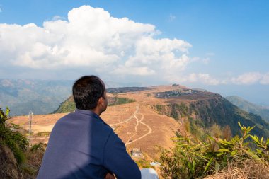 Genç adam düz gökyüzü ile dağın tepesindeki yatağı seyrediyor. Düz açı görüntüsü Nongnah meghalaya Hindistan 'da çekildi..