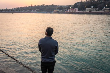 Ganj Nehri kıyısında duran izole genç adam Ganga Nehri kıyısı Rishikesh uttrakhand Hindistan 'da çekildi..