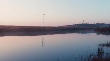 Sakin göl suyu yansıması ve gün doğumuyla sabah dramatik turuncu gökyüzü
