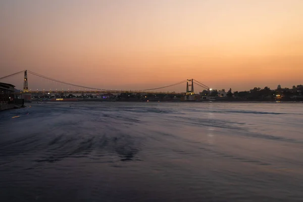 Ijzeren Hangbrug Met Zonsondergang Dramatische Hemel Wazig Stromend Rivierwater Avonds — Stockfoto