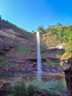 Şelale dağın tepesinden düşüyor, sabah mavi gökyüzü alçak açıyla.