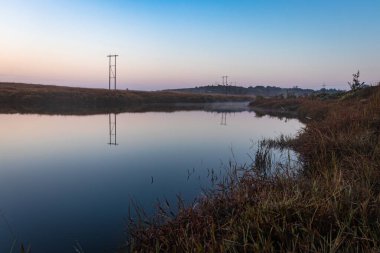 Sakin göl dramatik gündoğumu ile mavi gökyüzü yansıması sabah