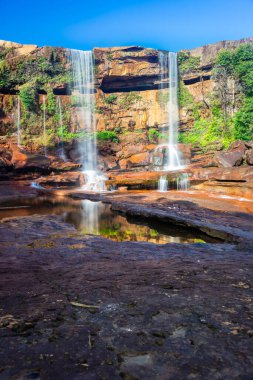 Dağın tepesinden düşen şelale yansıması ve mavi gökyüzü sabah alçak açıyla