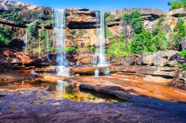 Dağın tepesinden düşen şelale yansıması ve düşük açılı mavi gökyüzü.