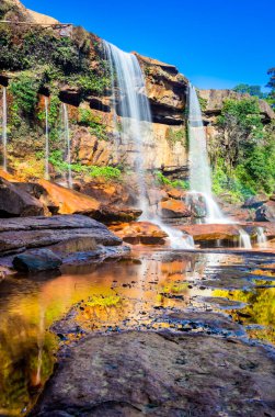 Dağın tepesinden düşen şelale yansıması ve mavi gökyüzü sabah alçak açıyla