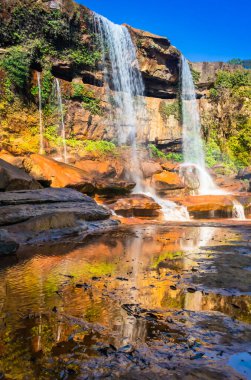 Şelale dağın tepesinden düşerken yansıma ve mavi gökyüzü sabah eşsiz bir açıyla