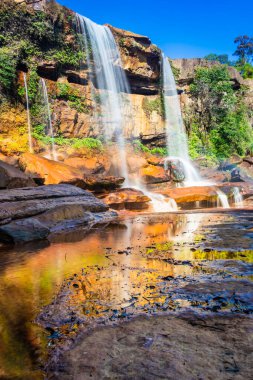 Şelale dağın tepesinden düşerken yansıma ve mavi gökyüzü sabah eşsiz bir açıyla