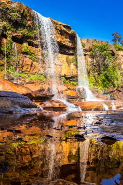 Şelale dağın tepesinden düşerken yansıma ve mavi gökyüzü sabah eşsiz bir açıyla