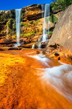 Şelale dağın tepesinden düşüyor. Mavi gökyüzü sabah eşsiz bir açıyla.