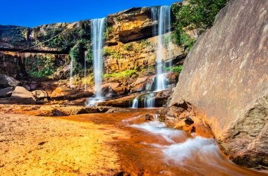 Şelale dağın tepesinden düşüyor. Mavi gökyüzü sabah eşsiz bir açıyla.